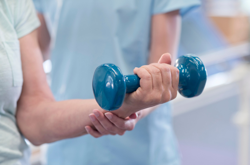 Physiotherapist holding a dumbbell during a rehabilitation session